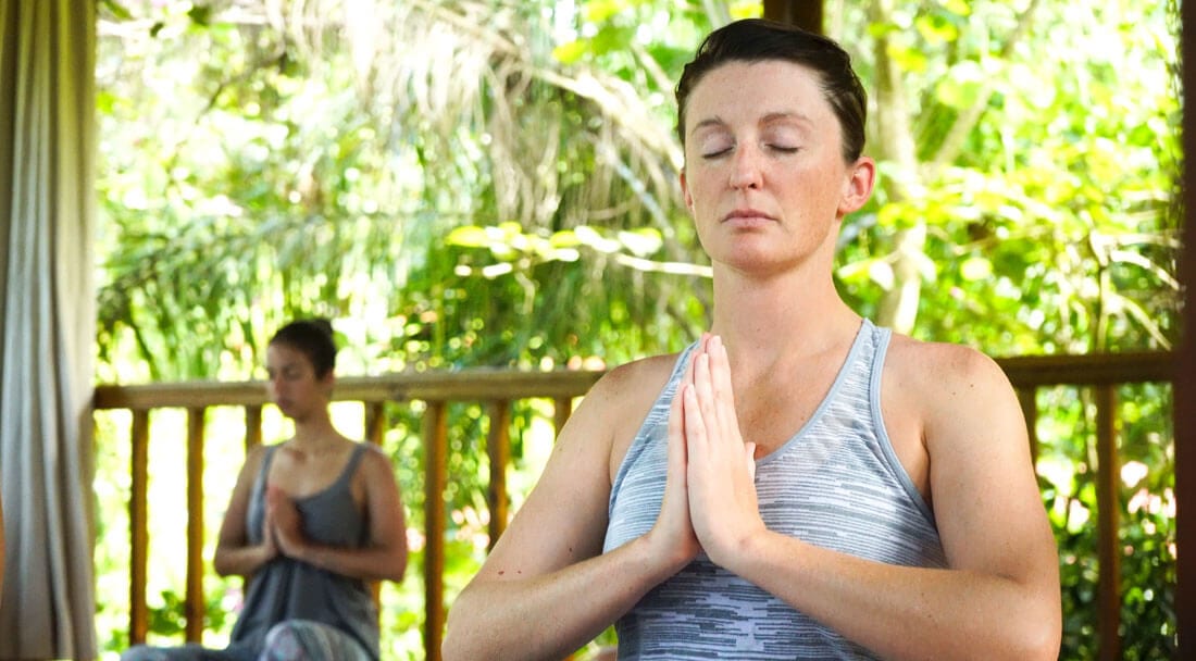 Two women in yoga class doing prayer hands aka anjali mudra