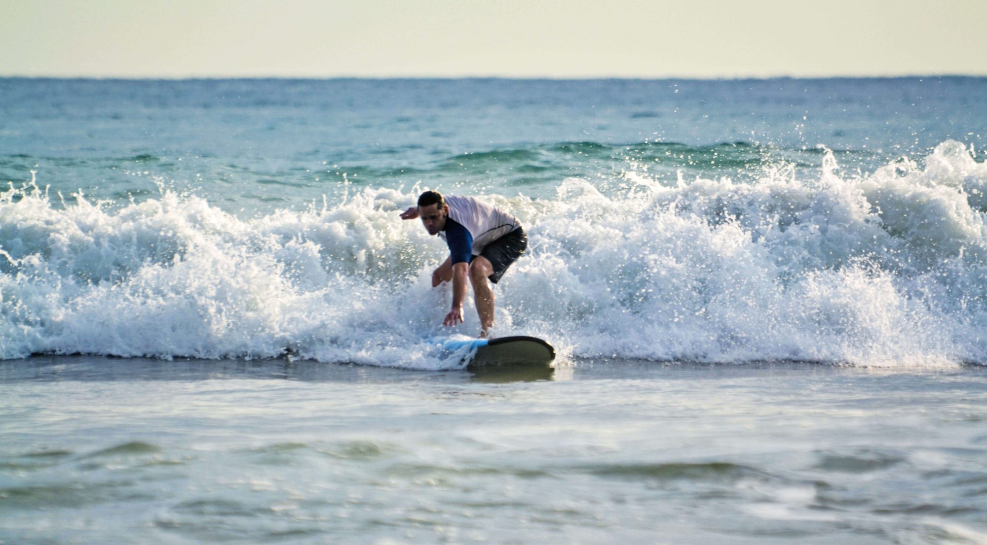 Beginner surfer catching a whitewater wave