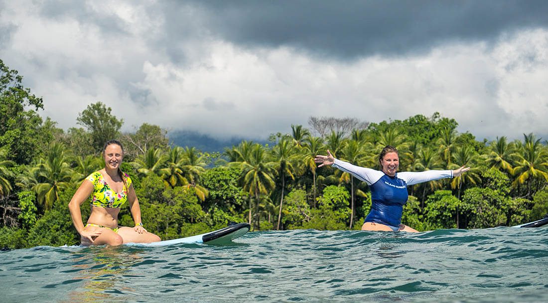 Smiling surfer girls talking in the lineup